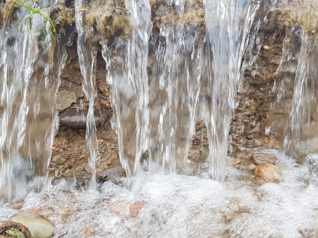 Una pequeña cascada de agua que fluye erosiona el suelo