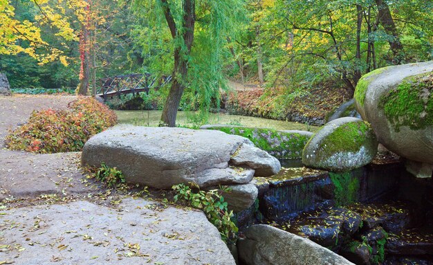 Pequeña cascada, estanque y puente en el parque de otoño