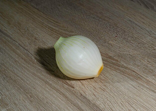 Foto una pequeña cebolla blanca cruda entera o cebolla francesa en una mesa de madera ligera