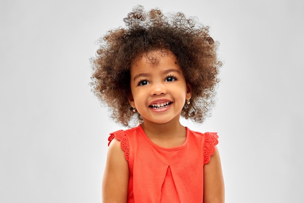 una pequeña chica afroamericana feliz sobre el gris