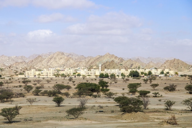 Pequena cidade moderna nos Emirados Árabes Unidos no deserto no sopé das montanhas