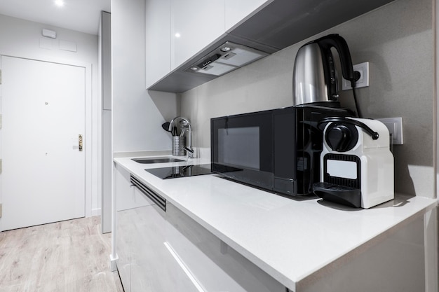 Foto pequeña cocina de un apartamento gris con fuerte de agua de microondas y máquina de cápsulas de café