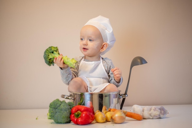 Pequeña cocinera preparando sopa de verduras en la cocina