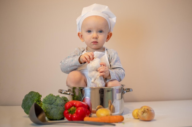 Pequeña cocinera preparando sopa de verduras en la cocina