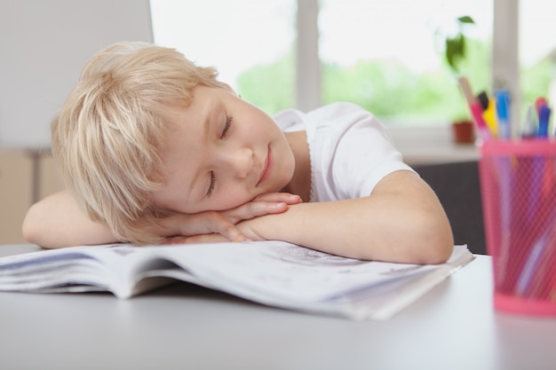 Pequeña colegiala adorable que duerme en su tarea