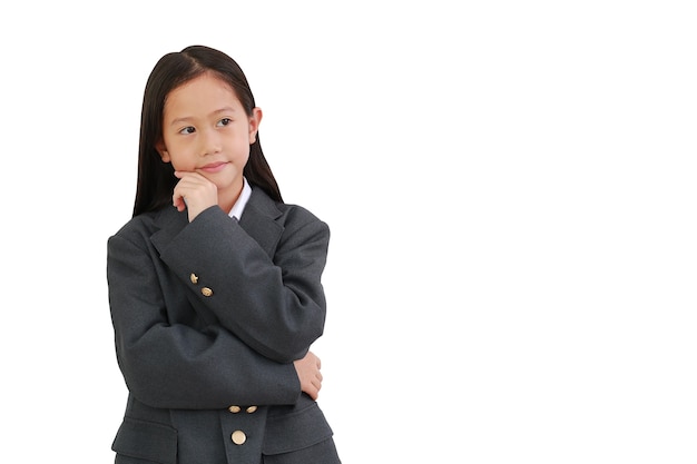 Pequeña colegiala en camisa de ropa formal, traje de negocios pensando y tocando la barbilla mientras mira a un lado