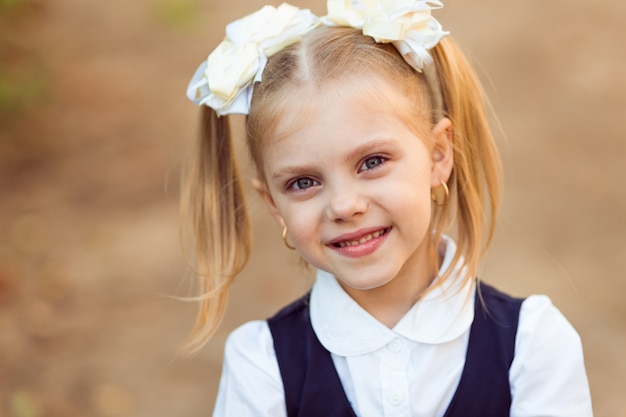 pequeña colegiala con coletas y lazos en uniforme escolar