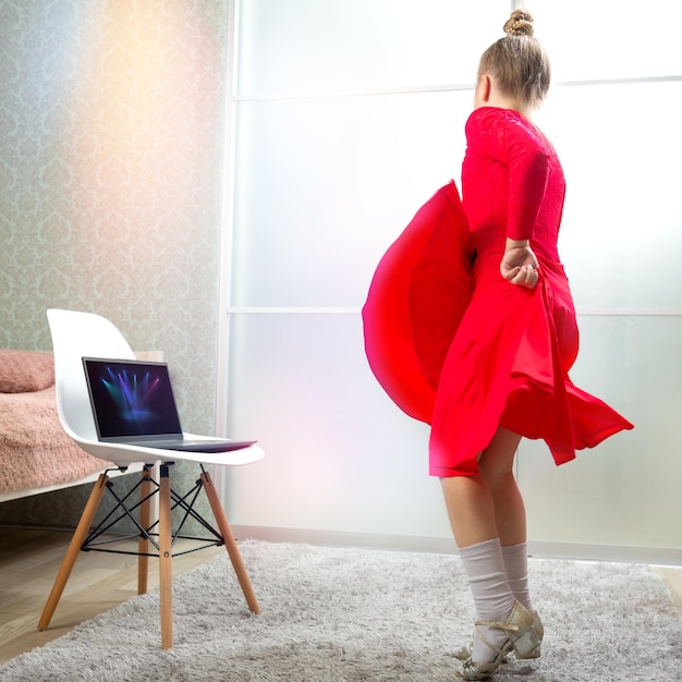 Pequena dançarina em um vestido de dança latino vermelho dança em casa aprende a dançar remotamente Aulas de dança em casa Aulas de dança online