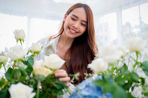 Pequena empresa ásia sorriso feminino florista organizando flores na loja de flores loja de design de flores felicidade jovem sorridente fazendo vaso de flores para clientes preparando trabalhos de flores em casa