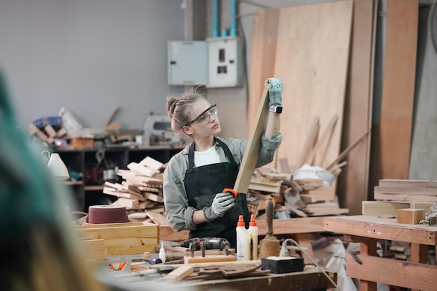 Pequena empresa de uma jovem Uma jovem atraente designer de carpinteiro trabalha na oficina