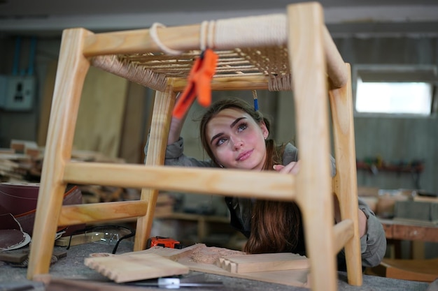 Pequeña empresa de una mujer joven en el fondo del taller de muebles