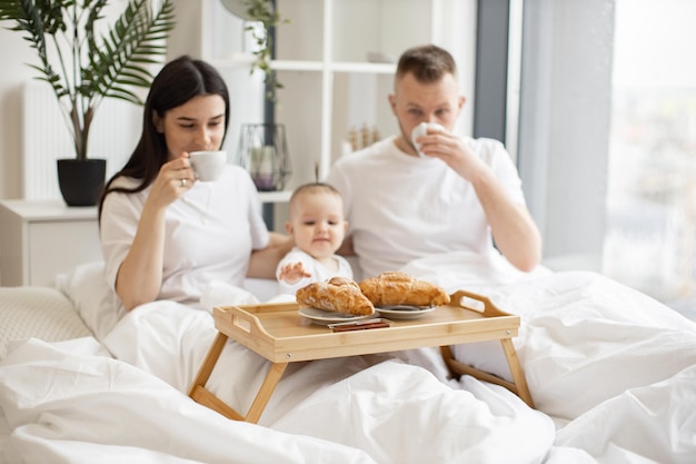 Pequena família de três pessoas fazendo uma refeição juntos no interior de casa