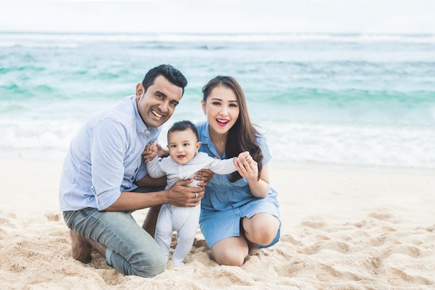 Pequeña familia feliz sonriendo mientras vacaciones en la playa