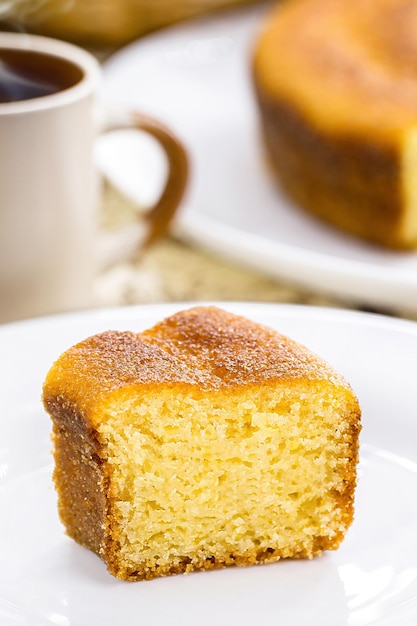 Pequena fatia de bolo de fubá típico bolo rural brasileiro feito com farinha de milho com café quente ao fundo café da manhã brasileiro