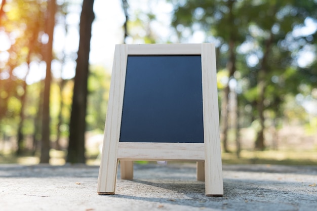 Pequeña A-frame pizarra con espacio en blanco para el texto o mensaje en la mesa de madera rústica en la mañana