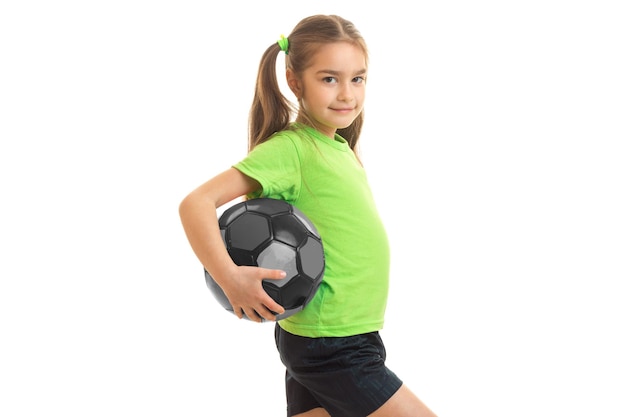 Foto pequena garota atlética com gigante segurando uma bola e sorrindo isolada no fundo branco