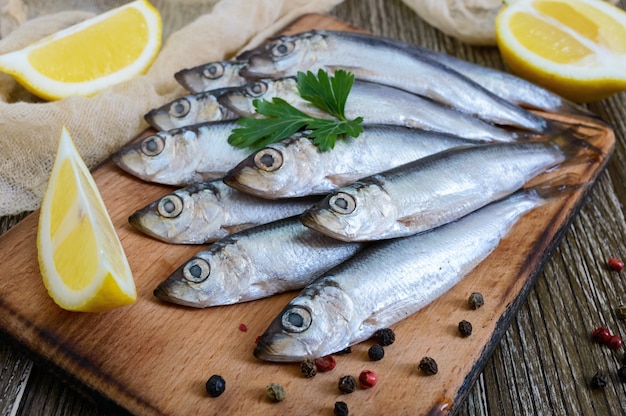 Una pequeña hamsa salada (espadín) con especias, limón sobre un fondo de madera.