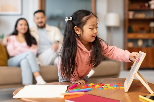 Pequeña hija asiática jugando con el tablero del alfabeto aprendiendo en casa