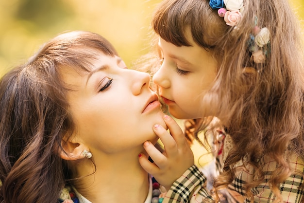 Una pequeña hija quiere besar a su madre y la toca suavemente