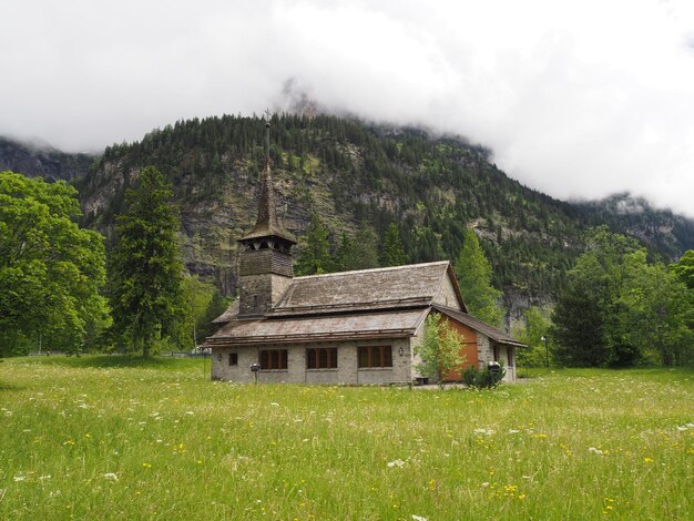 Foto una pequeña iglesia en un campo con montañas al fondo.