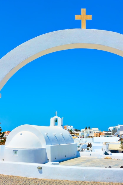 Pequeña iglesia griega blanca a través del arco con cruz, isla de Santorini, Grecia