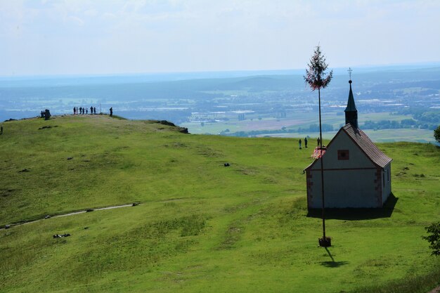 Pequeña iglesia vieja en una colina verde alta bajo el sol brillante y un camino