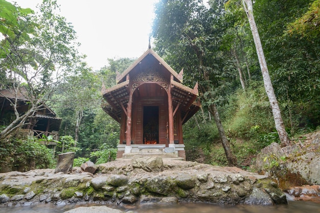 Pequena igreja de madeira no templo kantrapruksa em Mae Kampong, cercada por cachoeira e selva em Maekam