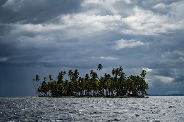 Pequeña isla tropical con palmeras de coco durante el concepto de viaje y aventura de clima nublado tormentoso