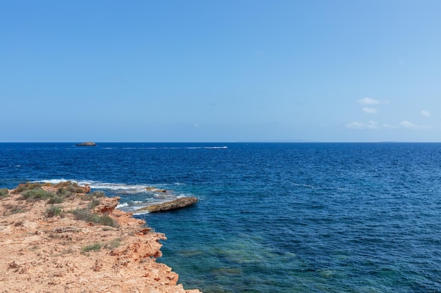 Pequeña lancha cruza las aguas de la bahía cerca del mar de la isla de Ibiza