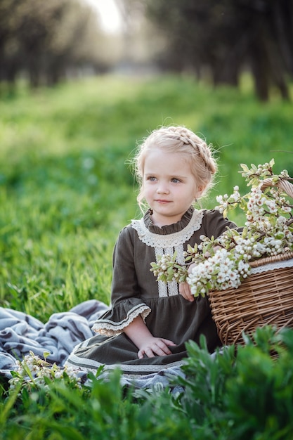 Pequena linda garota de vestido no jardim de flor. bebê fofo menina 3-4 anos segurando flores sobre a natureza. retrato de primavera. flor aromática e conceito vintage retrô.