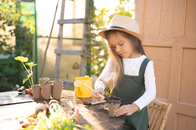 Foto una pequeña y linda granjera de pelo largo se dedica a plantar plantas. jardinería de hortalizas en la aldea. ecología.