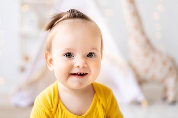 Una pequeña y linda niña está sentada en una luminosa y acogedora sala de juegos para niños Textiles para la guardería Retrato de un primer plano de un niño