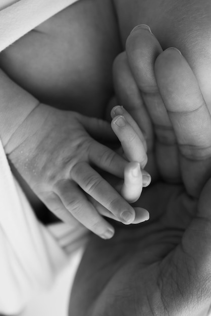 Foto pequena mão de um recém-nascido com dedos minúsculos cabeça nariz e orelha de um recém-nascido preto e branco descalço