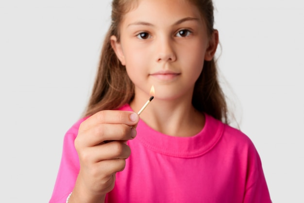 Pequena menina segurando fósforo aceso