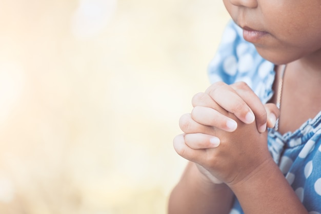 La pequeña muchacha asiática linda del niño que ruega con dobló su mano para el concepto de la fe, de la espiritualidad y de la religión