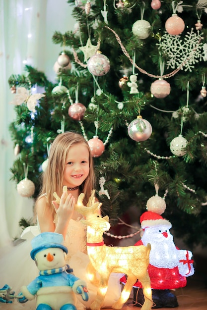 Pequeña muchacha linda cerca del árbol de navidad.