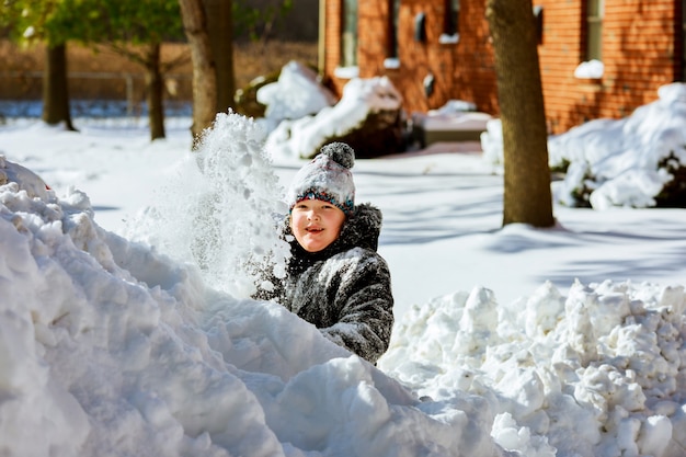 Pequeña muchacha sonriente feliz al aire libre en la nieve en la ropa del invierno