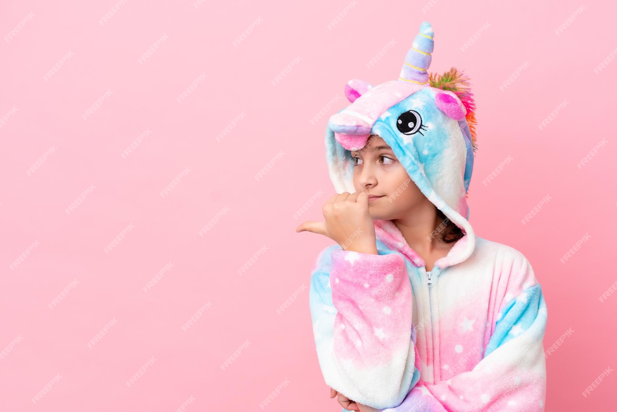 Pequeña mujer caucásica un pijama de unicornio aislado en un fondo apuntando un lado para presentar un | Foto Premium