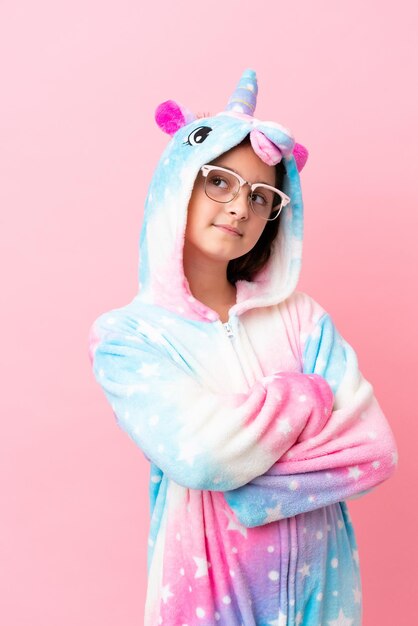 Pequeña mujer caucásica con un pijama de unicornio aislado de fondo rosa