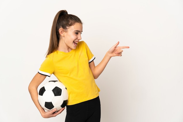 Foto pequeña mujer de jugador de fútbol aislada en la pared blanca que señala el dedo hacia un lado y presenta un producto