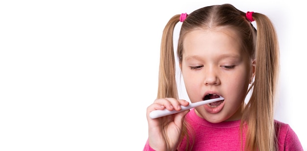 Pequeña mujer rubia linda cepillarse los dientes con un cepillo de dientes blanco sobre fondo blanco