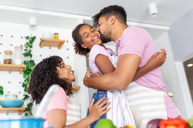 Pequeña niña adorable preparando pastel con padres amorosos y cariñosos en la cocina doméstica familia joven disfruta del proceso de cocina en casa enseñando a los niños a pasar el fin de semana juntos ayudar al concepto de paternidad feliz