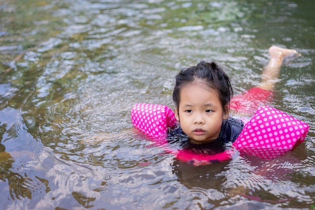 Pequeña niña asiática nadando en el río