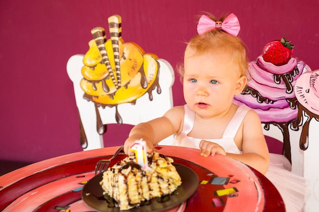 Pequeña niña feliz celebrando el primer cumpleaños Kid y su primer pastel en la fiesta Infancia