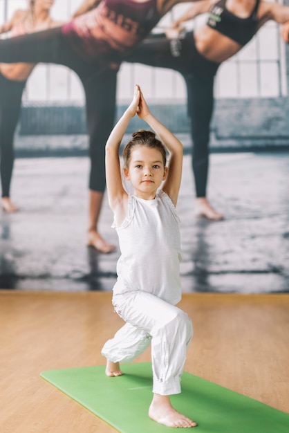 Pequeña niña inocente haciendo yoga en el gimnasio