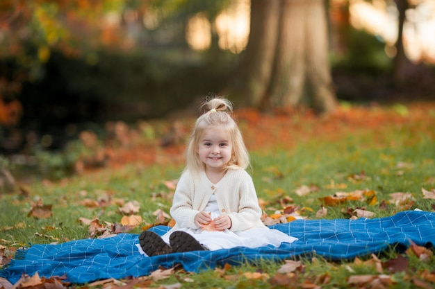 Pequeña niña linda de cabello blanco de 3 años en el parque de otoño Caminar por el bosque