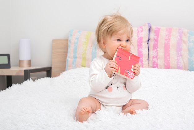 Pequeña niña linda en dormitorio con el libro.