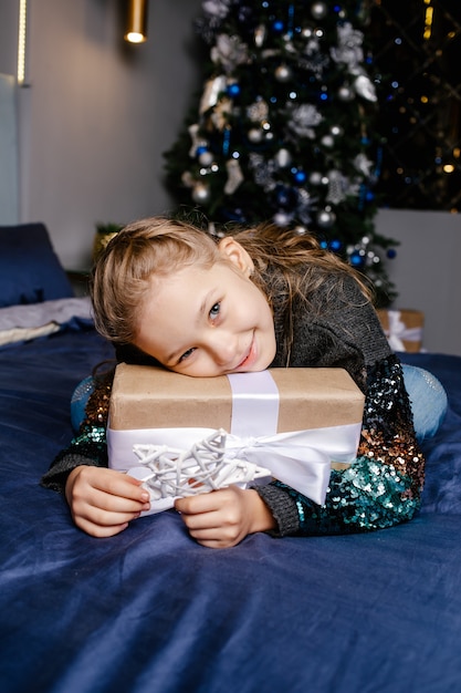 La pequeña niña linda recibió un regalo de vacaciones. Disfruta recibiendo regalos. Niño emocionado por desempacar su regalo. Concepto de Navidad, vacaciones e infancia.