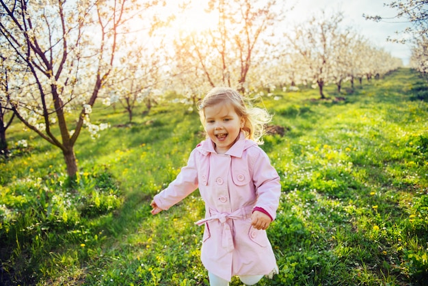 Foto pequeña niña que corre entre los árboles en flor al atardecer. arkansas