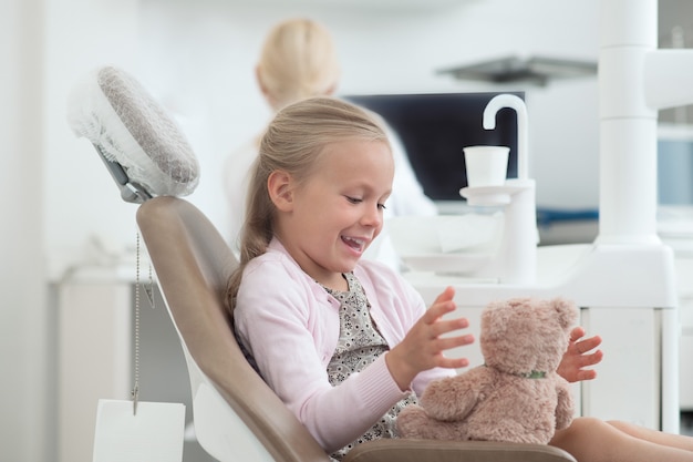 Una pequeña niña sentada en la silla del dentista.